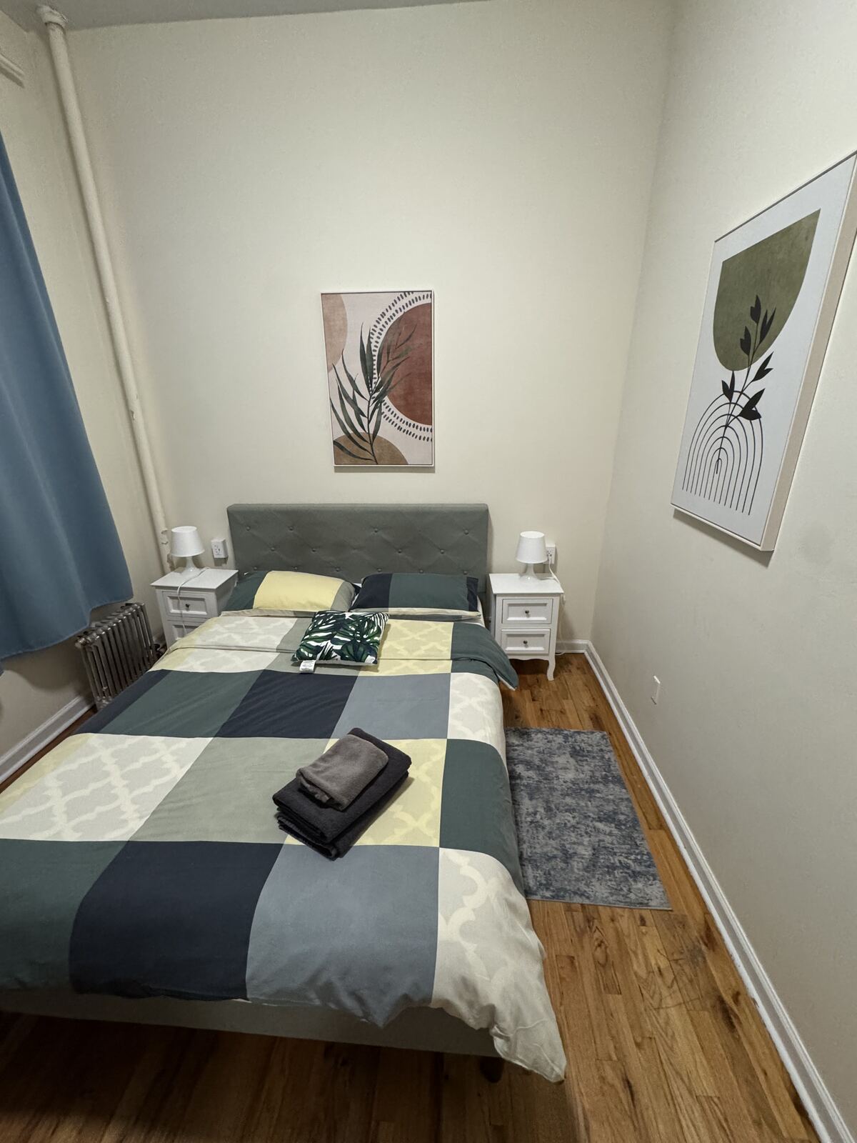 Finished bedroom with a blue and green quilt, wall art, and hardwood floor