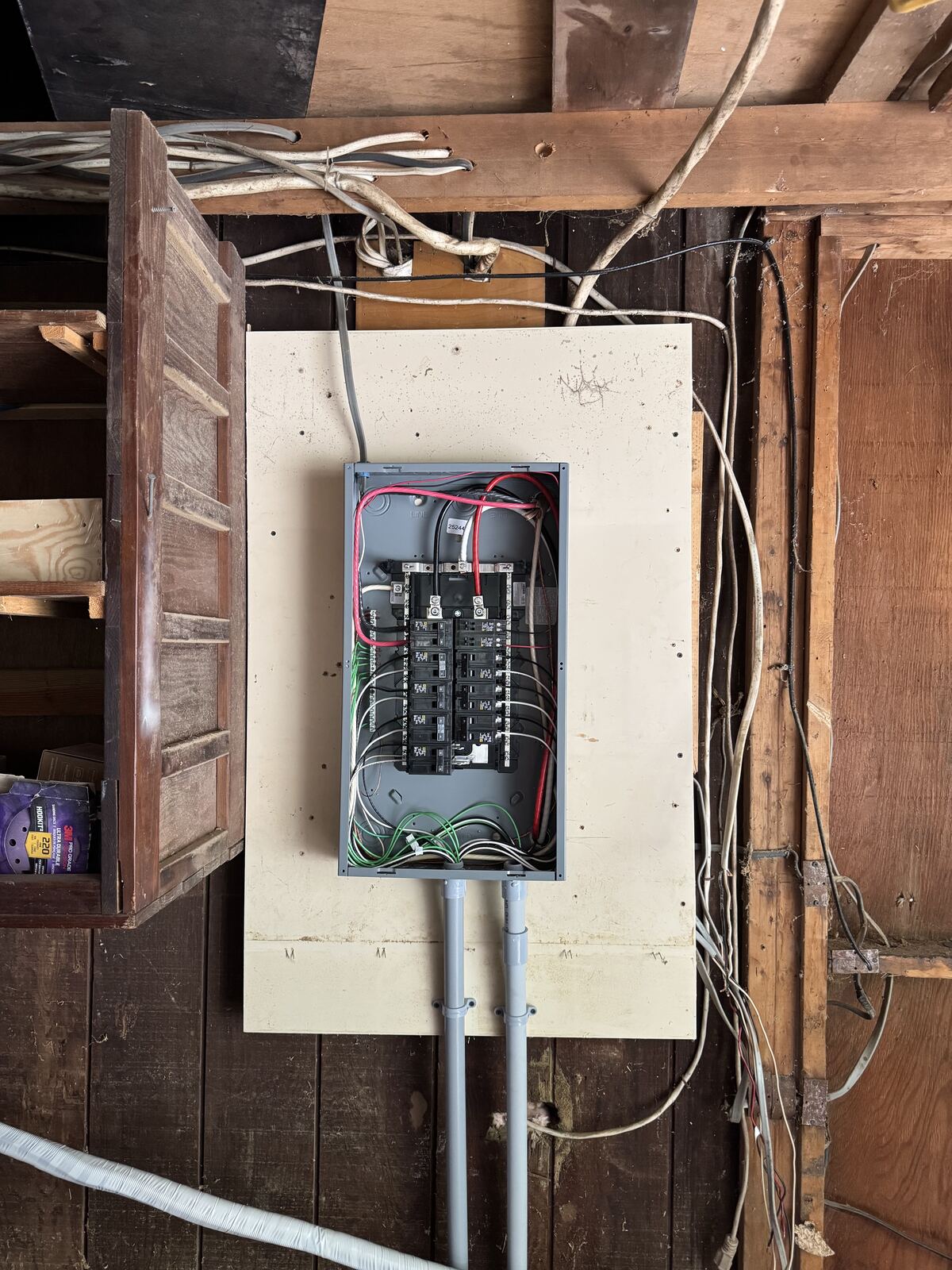 Open electrical panel with connected wiring in an unfinished wall area