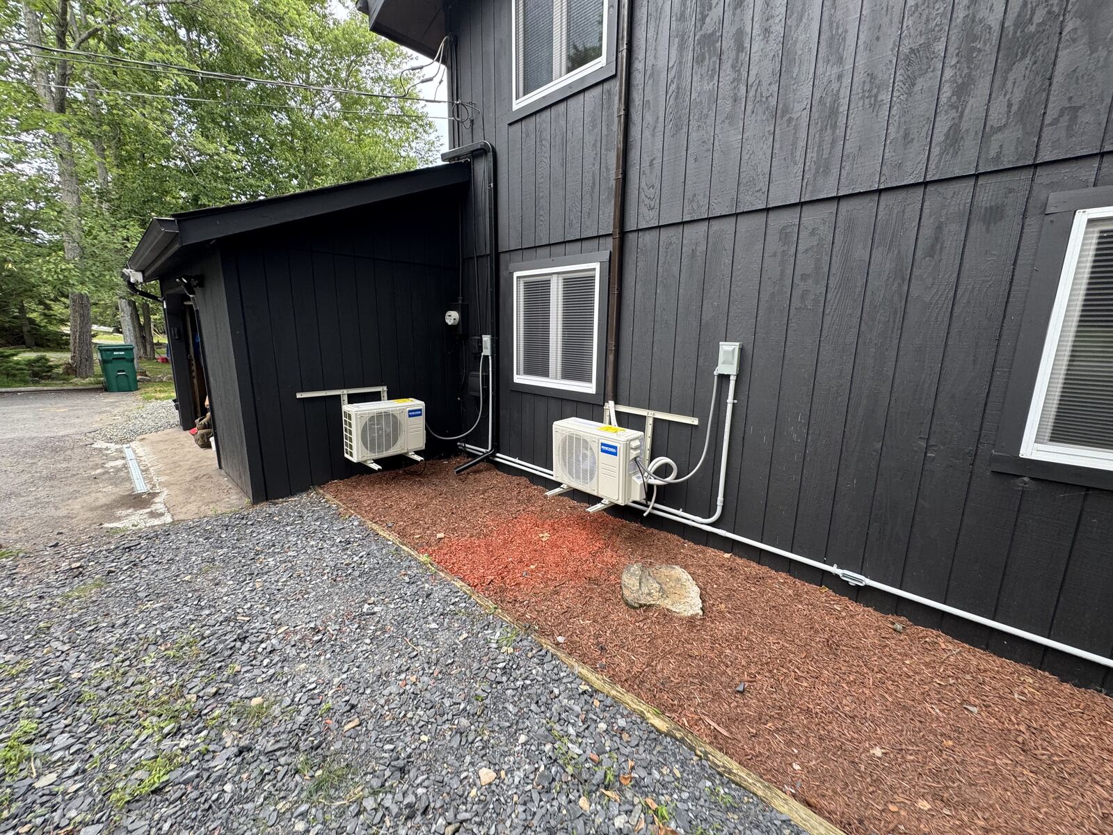 Side view of two mini-split condenser units mounted beside a black exterior wall
