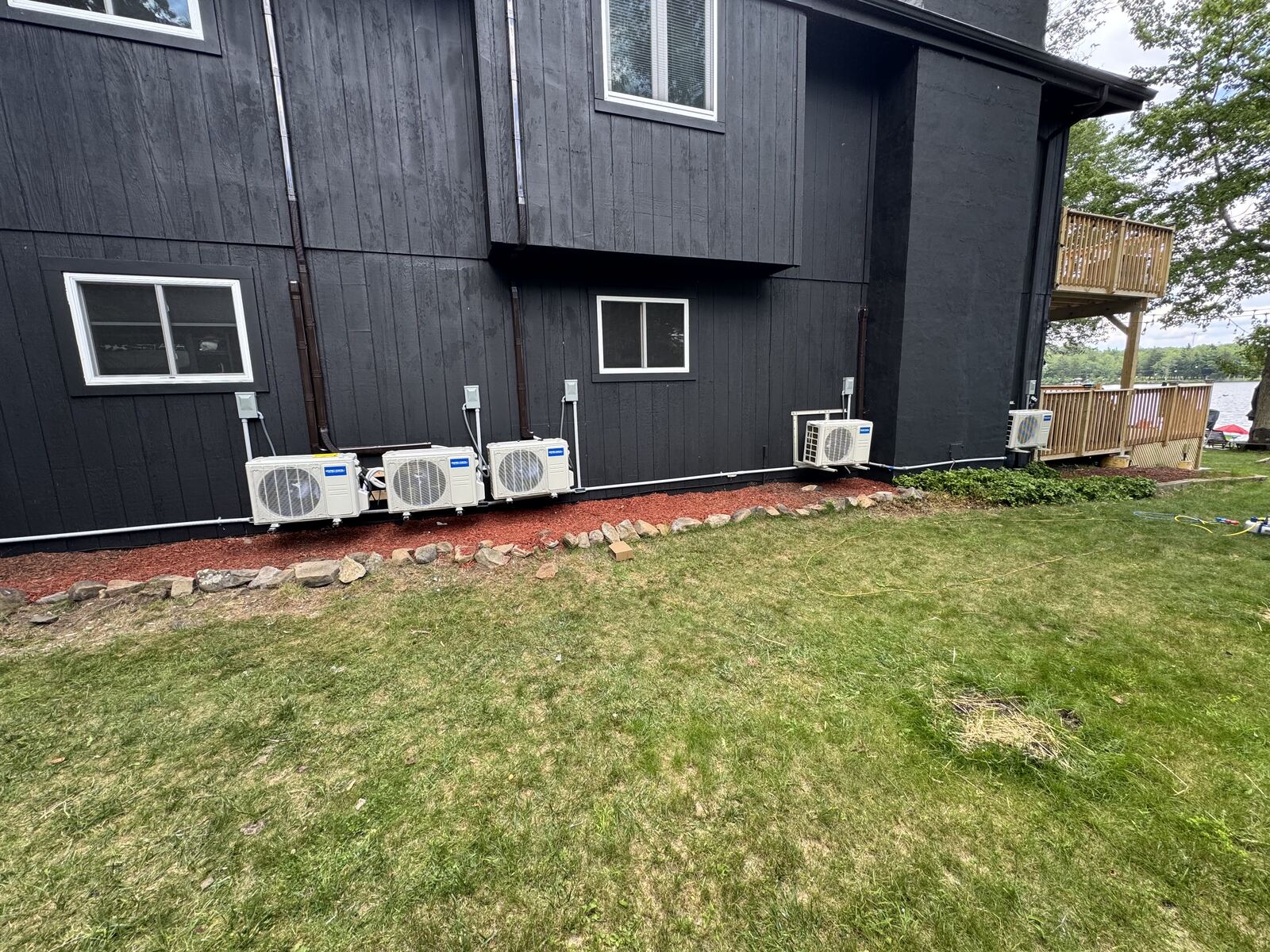 Black exterior wall with multiple mini-split condenser units and conduit