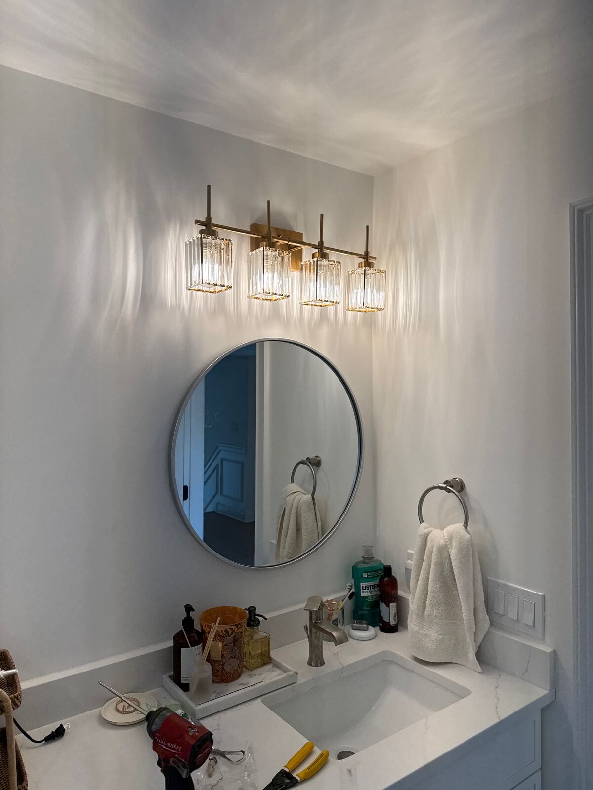 Bathroom vanity with a round mirror and a four-light fixture